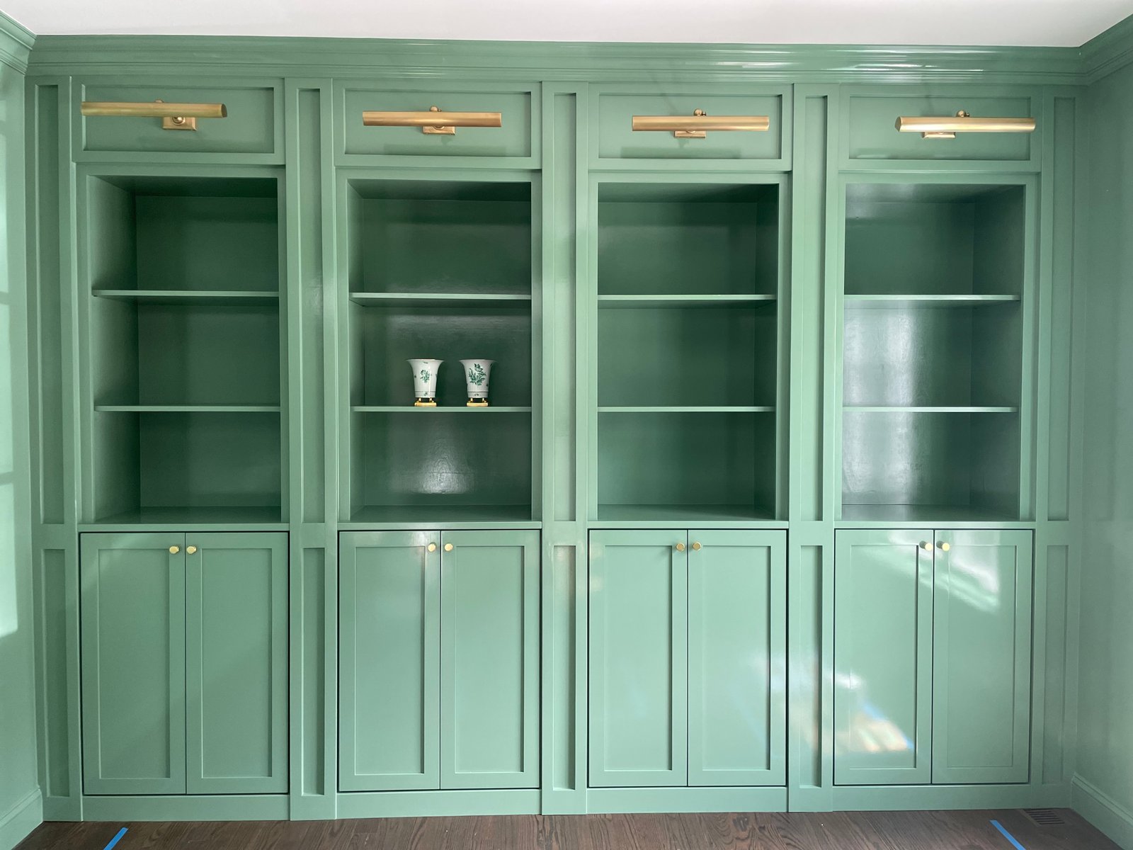 After painting: the same four bays finished green, with brass lights and cabinet knobs