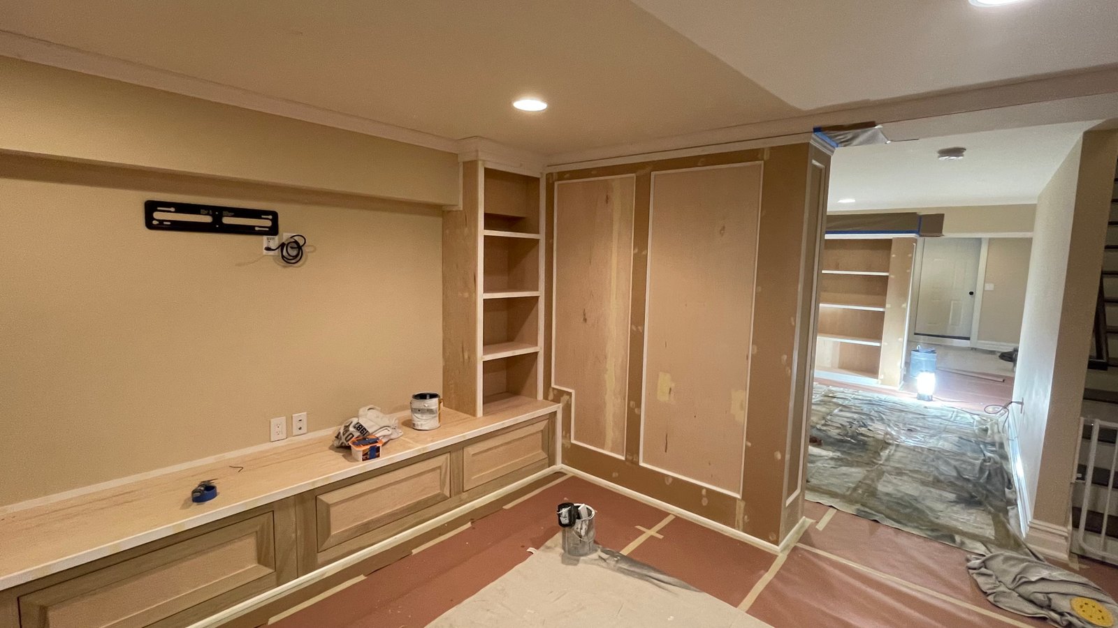 Before painting: unfinished media-wall shelves and right-hand paneling with floor protection